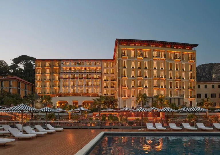 Exterior view of hotel building illuminated with an outdoor pool in front