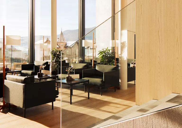 Hotel lounge with large windows and a glass staircase to the right