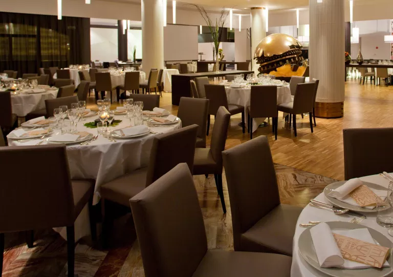 Restaurant with brown, cushioned chairs and white cloths on dining tables