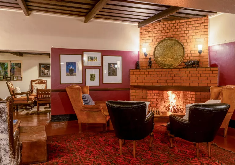 Leather chairs surrounding a brick fireplace, with paintings on the walls