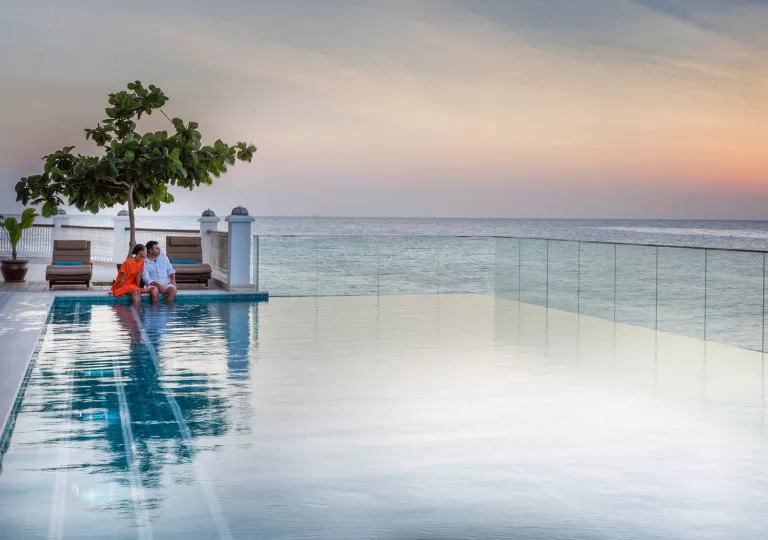 Outdoor infinity pool, with man and woman sitting with their feet in the pool
