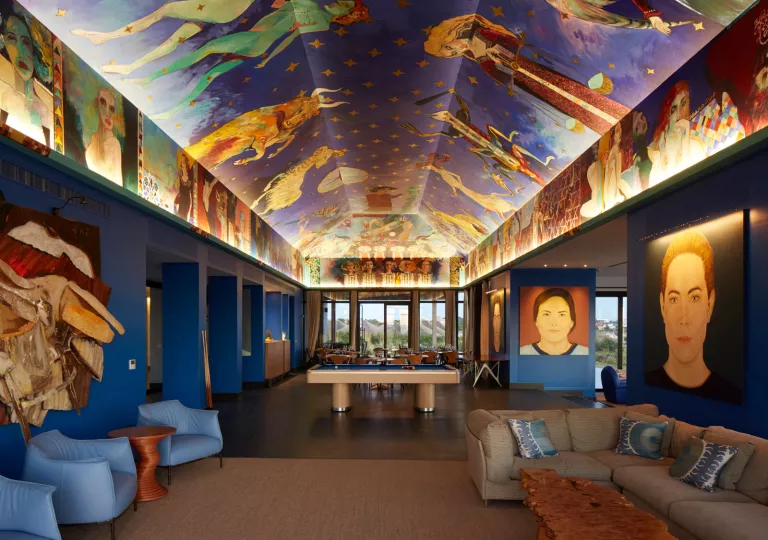 Long, blue room with murals on the ceiling and the walls, with couches along the room