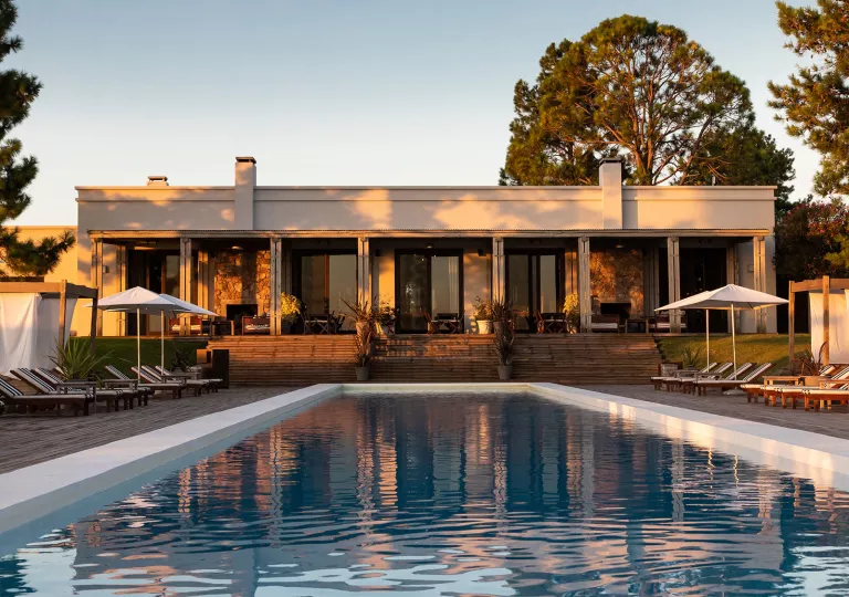 View of outdoor pool with a large, white building in the back