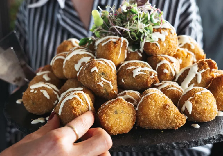 Person holding a large plate of fried food