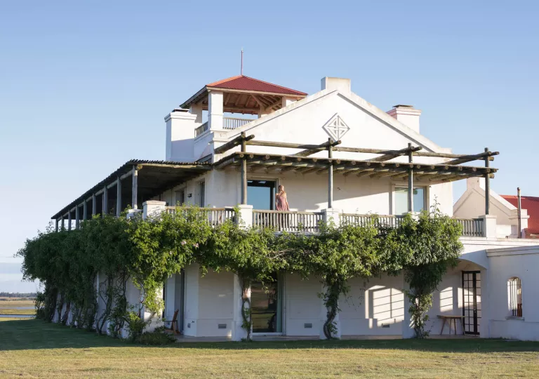 Exterior view of large, white building with two floors and branches surrounding the walls