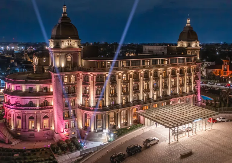Exterior view of European-style hotel building, illuminated by bright pink and white lights