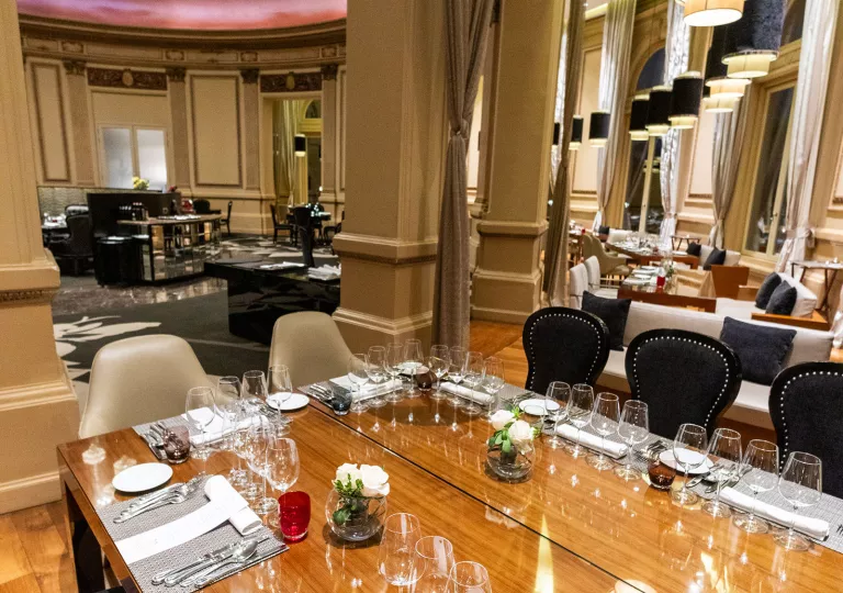 Dining hall area with wooden tables and wine glasses on each table