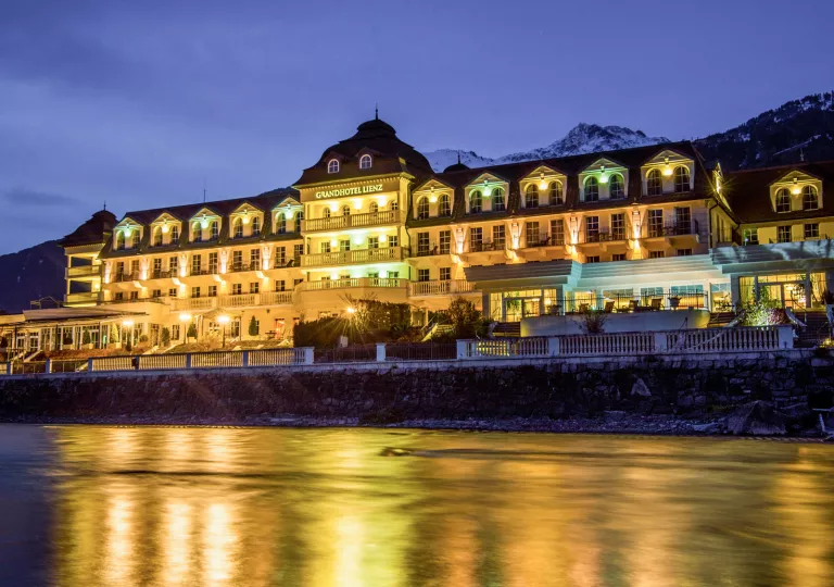 Exterior view of illuminated hotel building with a large lake in front
