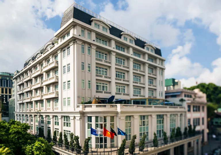 Daytime, exterior view of white multi-story building with flags in front