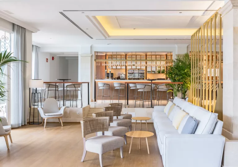 Hotel lounge area with cushioned sofas and a bar counter in the background