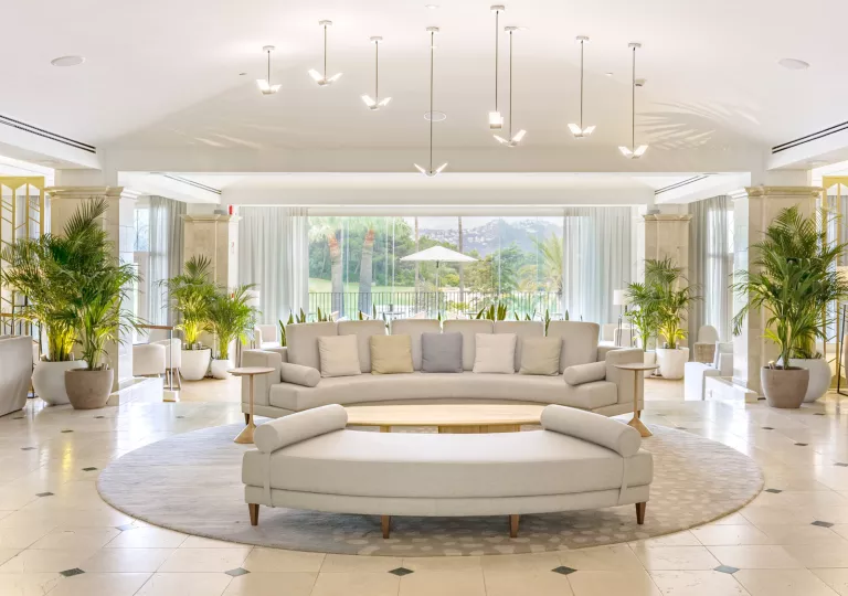 Large room with large, cushioned sofas and large windows in the back