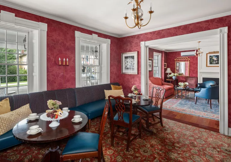 Hotel lobby with red walls and cushioned chairs and wooden, circular tables