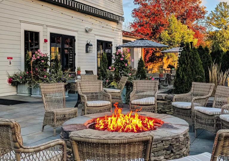 Outdoor firepit with woven chairs surrounding it in a circle