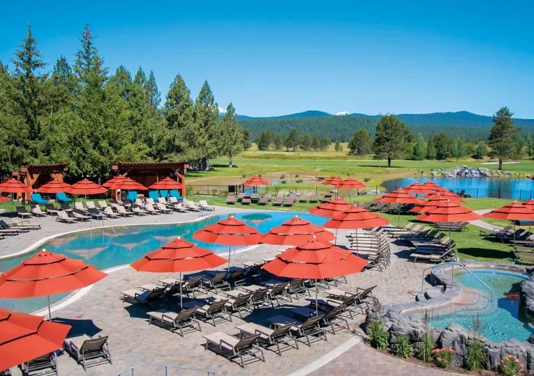 Outdoor pool area with reclining chairs and red umbrellas