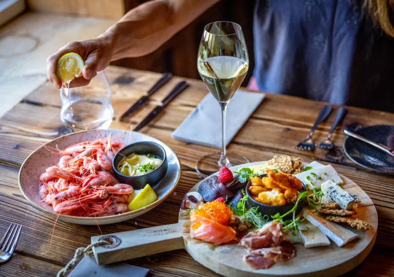 Plate with boiled seafood, with a charcuterie board next to it