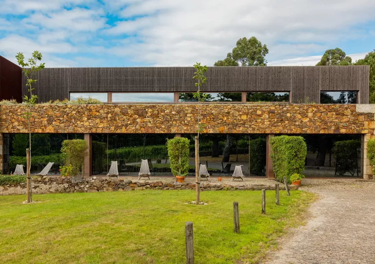 Exterior view of a modern stone and wood building, with a grass area in front