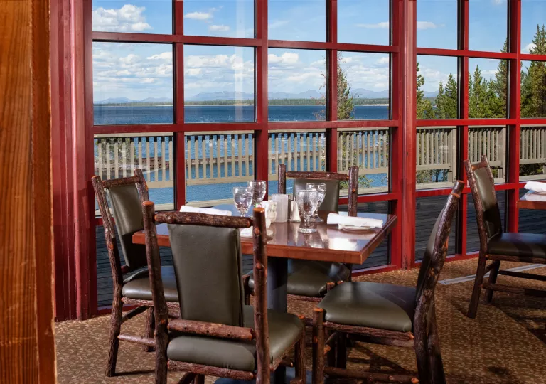 Restaurant dining area with wooden chairs and tables next to large windows