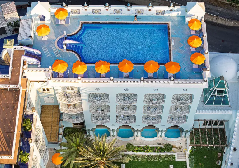 Aerial view of the rooftop pool and sun deck with bright orange umbrellas at the Palazzo Manzi Terme &amp; Spa in Casamicciola Terme on the island of Ischia, Italy.