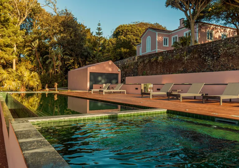 Outdoor pool with stone walls and reclining chairs