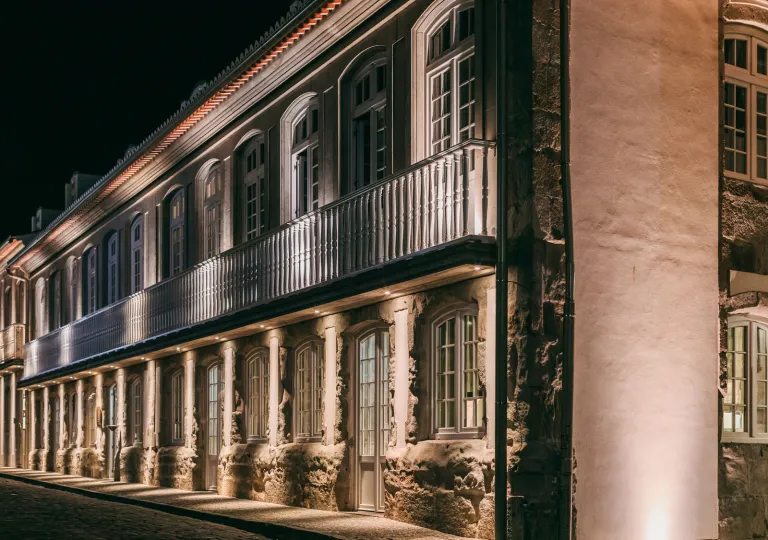 Evening, exterior view of stone hotel building with exposed brick walls