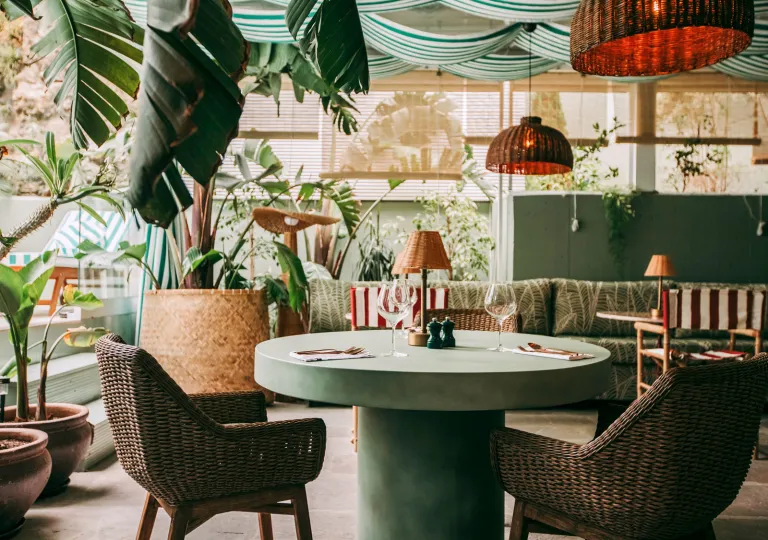 Outdoor patio and dining area with a green, circular table and woven chairs