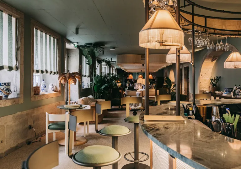 Bar and lounge with a marble countertop and green, cushioned bar stools