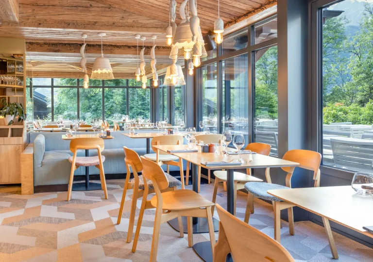 Restaurant dining room with wooden chairs and tables, with tall windows