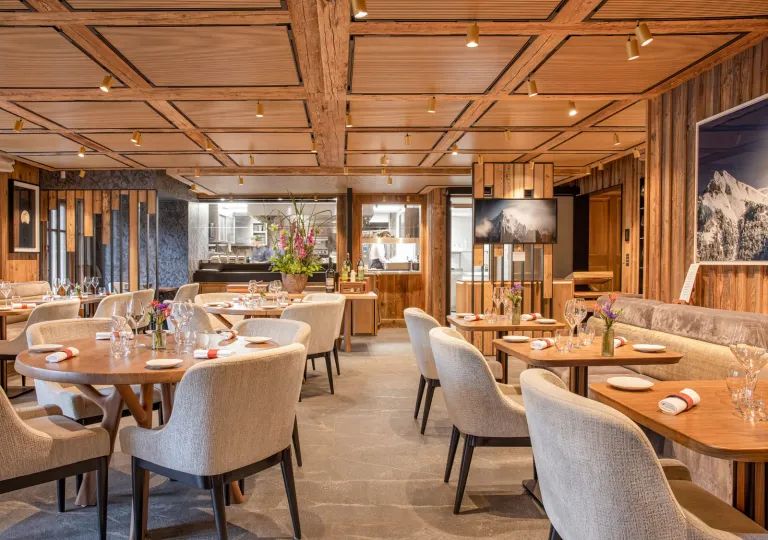 Indoor restaurant with beige, cushioned chairs and wooden tables