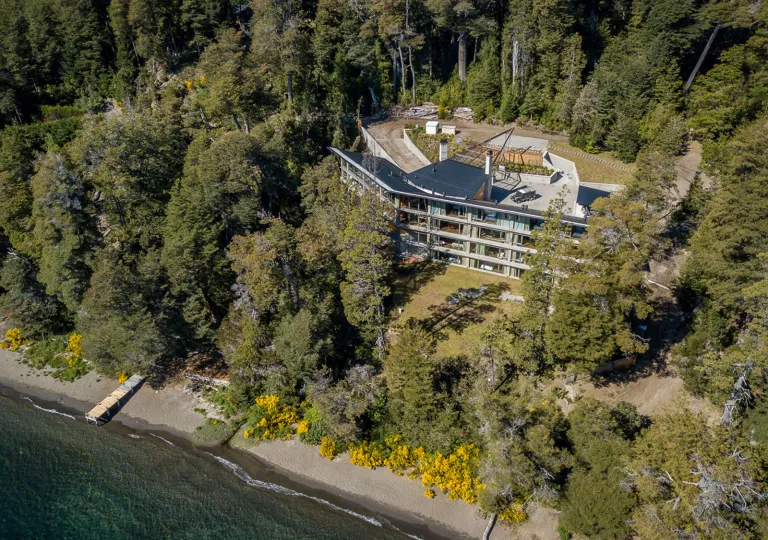 Aerial view shows the lakeside  multi-level Calfuco Wine Hotel &amp; Spa surrounded by forest in Neuquén, Argentina.
