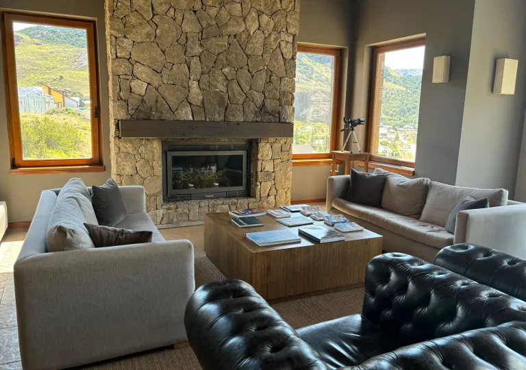 Lounge seating area with cushioned, beige couches in front of a stone fireplace