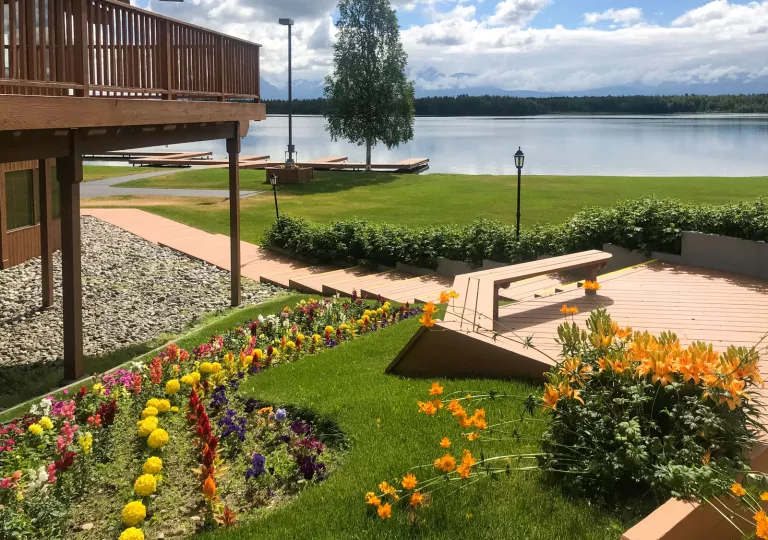 Grass field with garden next to a building, with a lake in the background