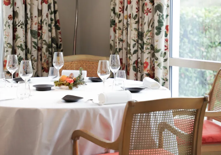 Circular, white dining table with wine glasses and table cloths