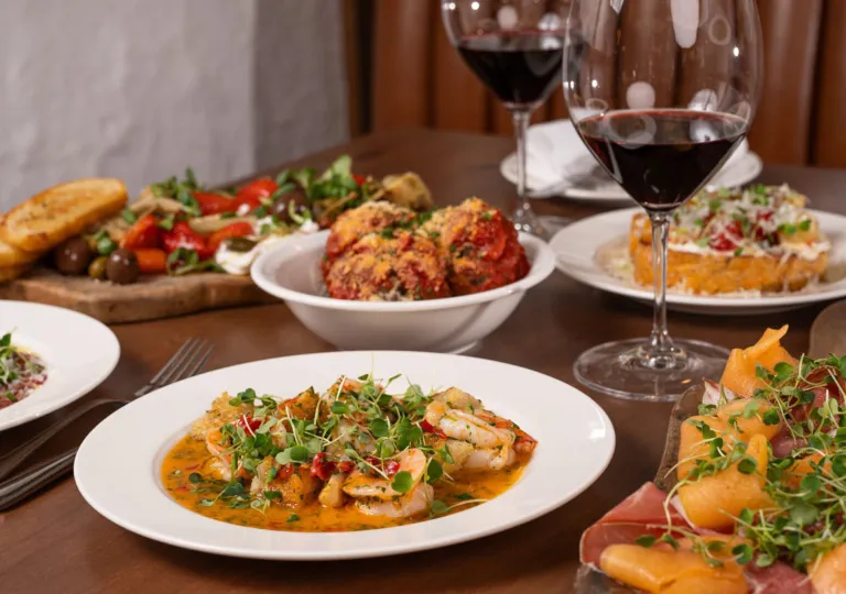 Plates of pasta and other food on a wooden table