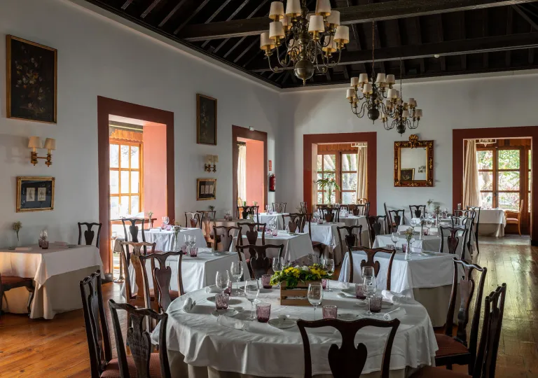 Restaurant with circular tables with white table clothes, and wooden chairs