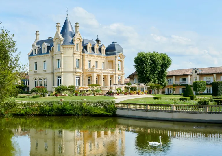 Exterior view of yellow, castle-like building with a lake in front