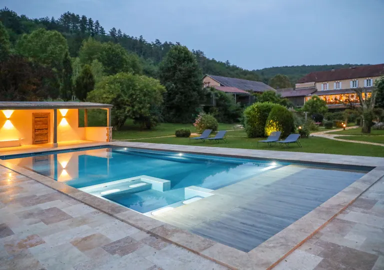 Outdoor pool with lit coverings and large trees in the background