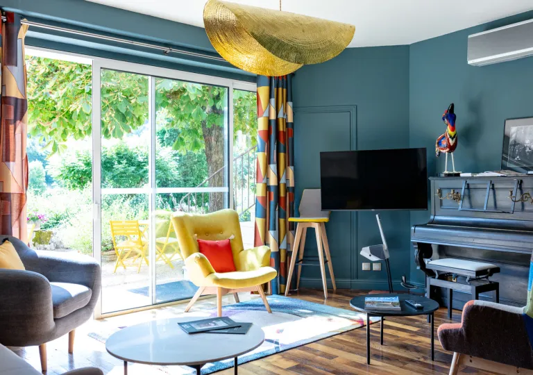 Blue room, with a television mounted on the wall, with a large window looking out to a garden