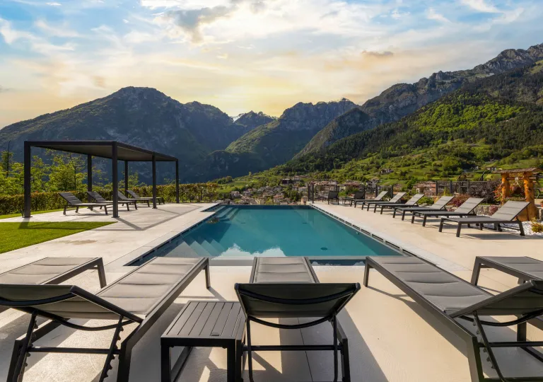 Outdoor pool surrounded by gray chairs with large mountains in the background