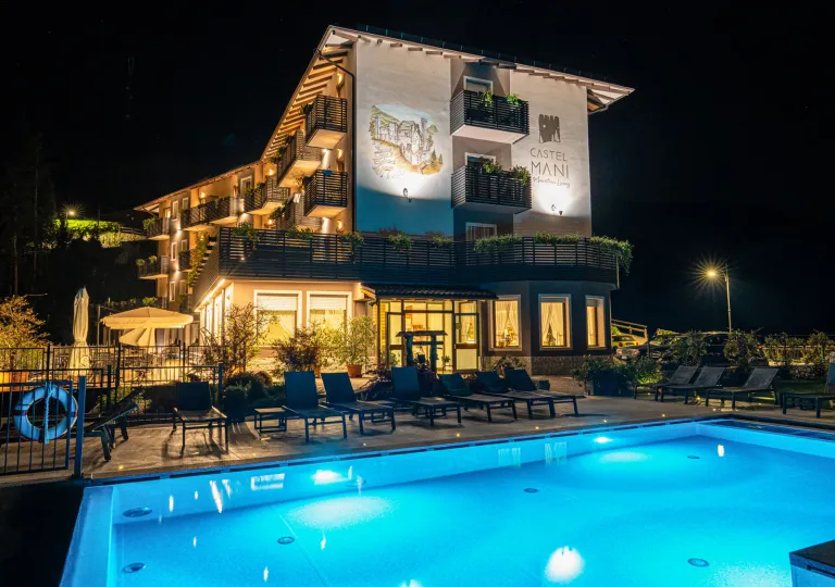 Exterior, evening view of a hotel building with an illuminated pool in front
