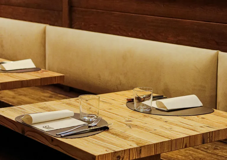 Wooden dining table with handkerchiefs, silverware and glasses on the table