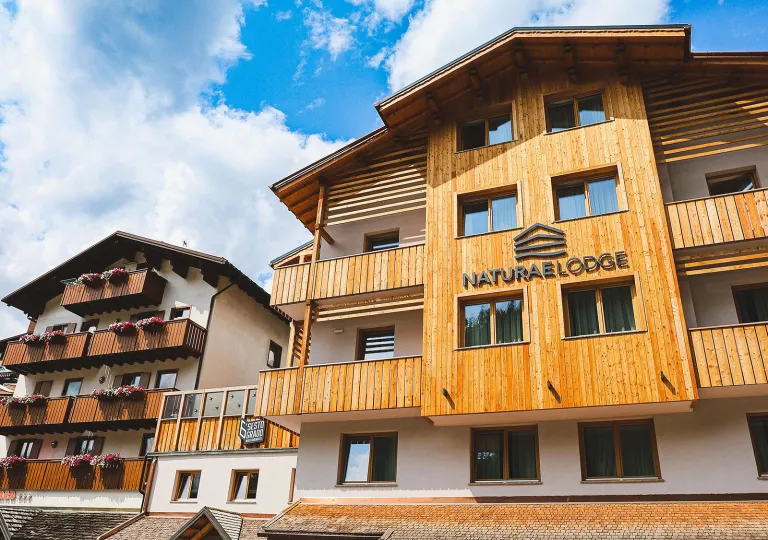 Exterior view of wood and white hotel building with outdoor balconies