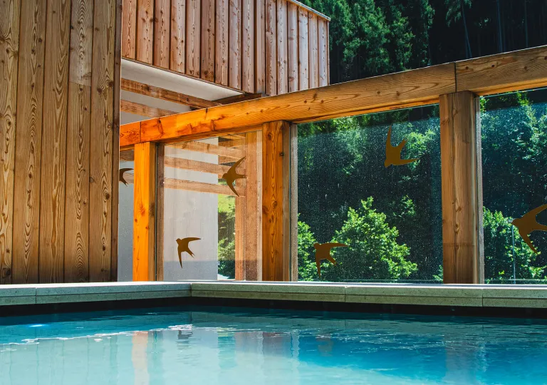 Outdoor pool with large, wooden pillars and a wooden lodge to the left