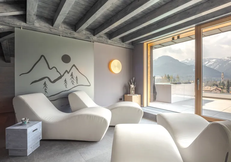 White, reclining lounge chairs looking out towards two glass doors looking towards tall mountains