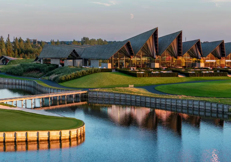Exterior, evening view of hotel building with a grass lawn and large lake in front