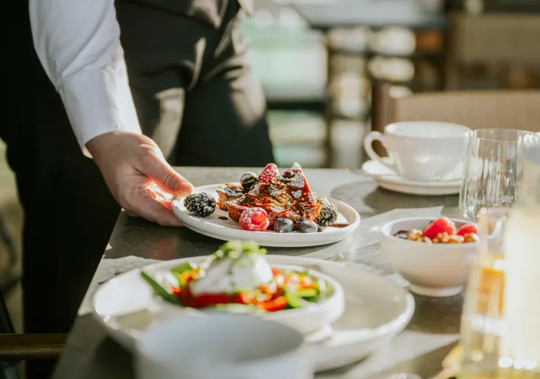 Waiter serving a plate of food onto a white table