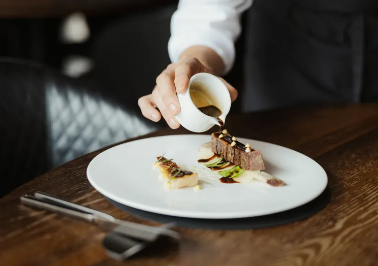 Man pouring chocolate over a plate with dessert
