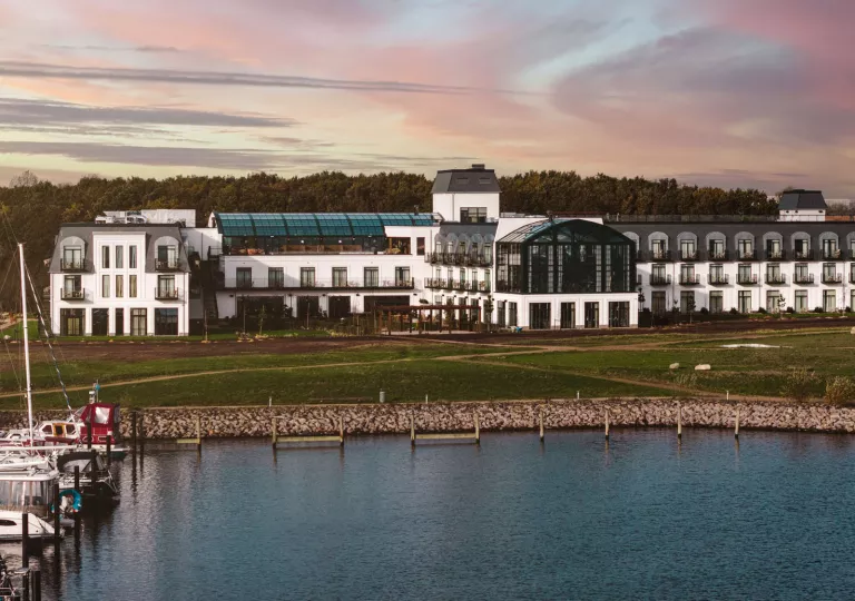 Exterior view of large, white building with outdoor balconies and large windows