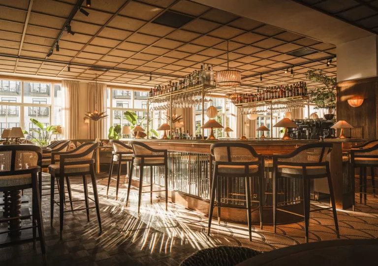 Indoor bar and lounge with tall stools and shelves holding bottles of liquor
