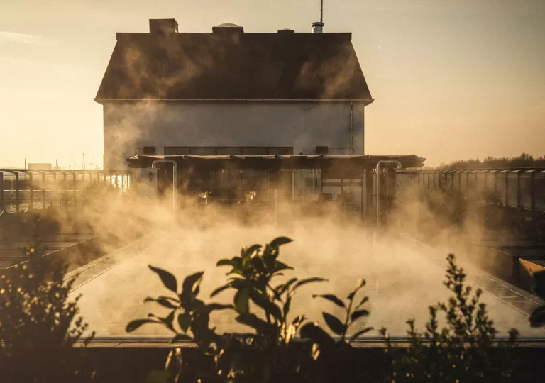 Outdoor pool with steam coming out with a large building in the background