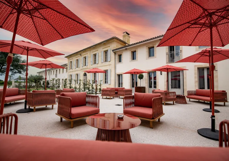 Outdoor patio with red, cushioned chairs and red umbrellas